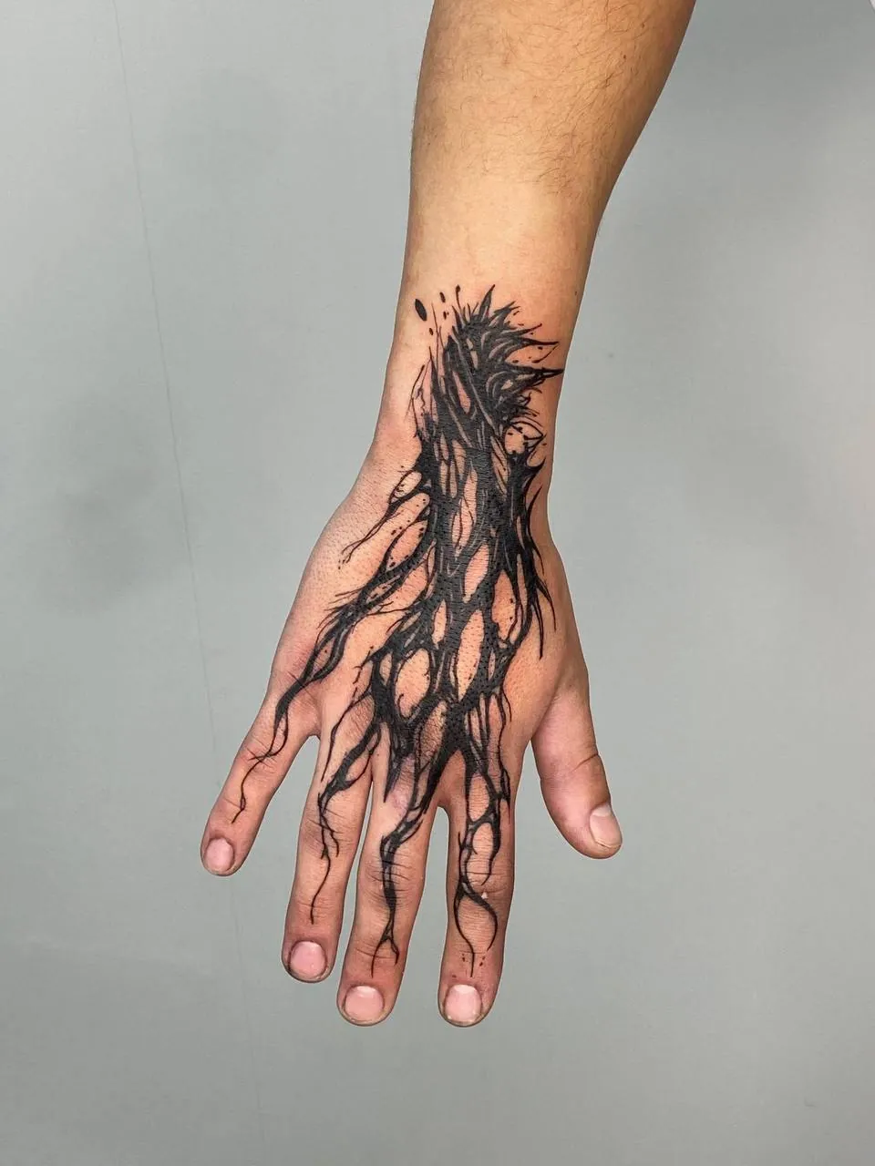 Blackwork tattoo of dark branching roots spreading over the back of the hand and the fingers