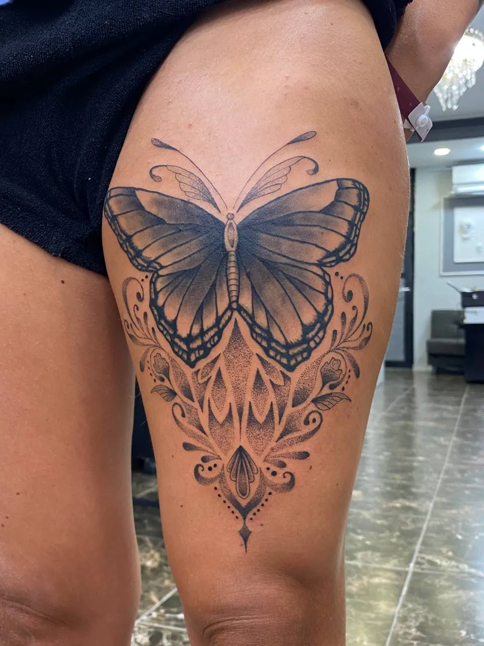 Black and grey butterfly above an ornamental pattern on the thigh