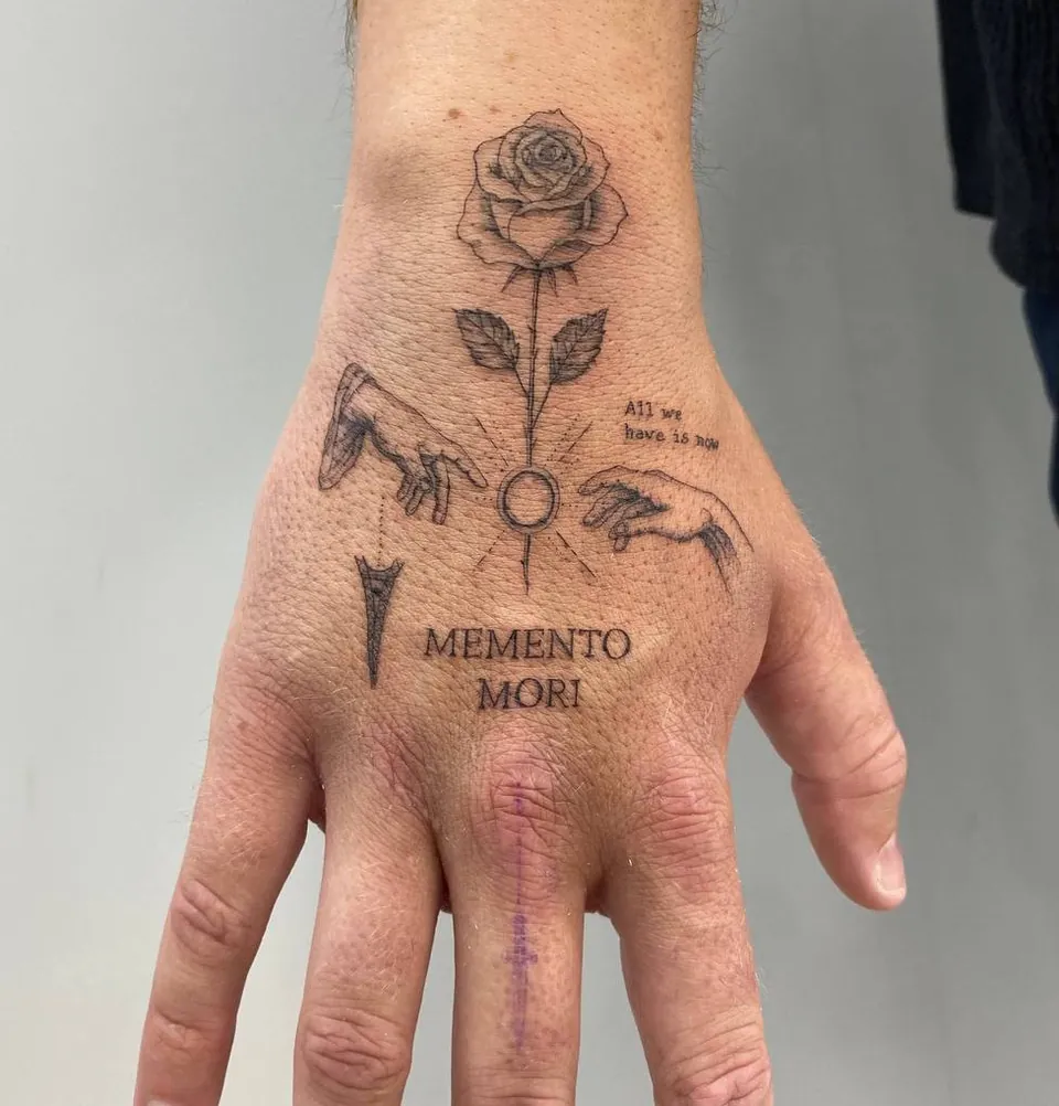 Fine-line hand tattoo of a rose, two reaching hands and the words Memento Mori