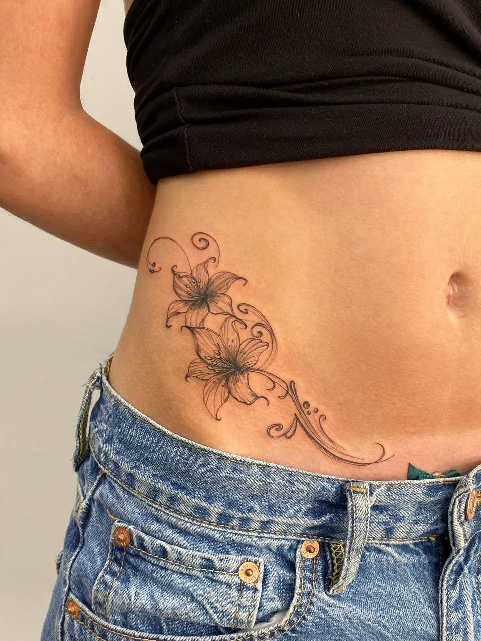 Fine-line lilies with a curling flourish on the hip